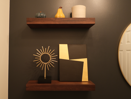 Two dark wooden floating shelves holding small ornaments and framed artwork