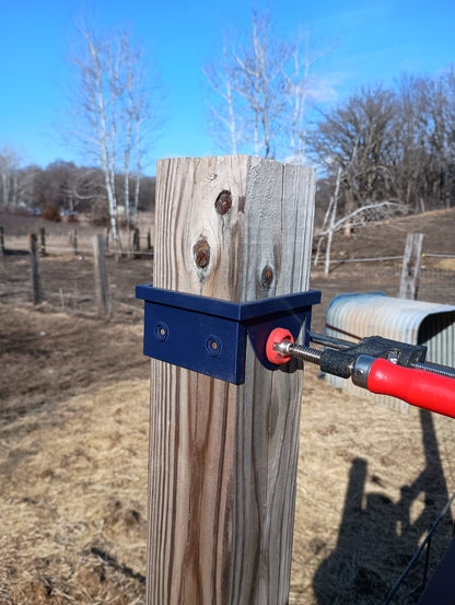 Black 3D printed 4x4 circular saw cutting guide clamped around a wooden fence post, viewed from the opposite side with red clamp handle