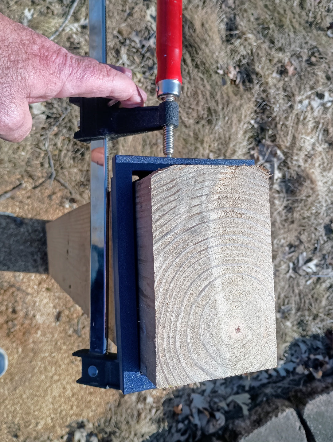 View from the end of a wooden post showing a fitted black 3D printed cutting guide secured with a clamp