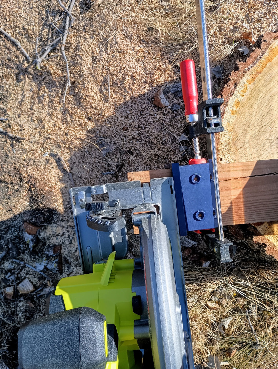 Top view of circular saw positioned beside a clamped 3D printed post cutting guide on a wooden beam