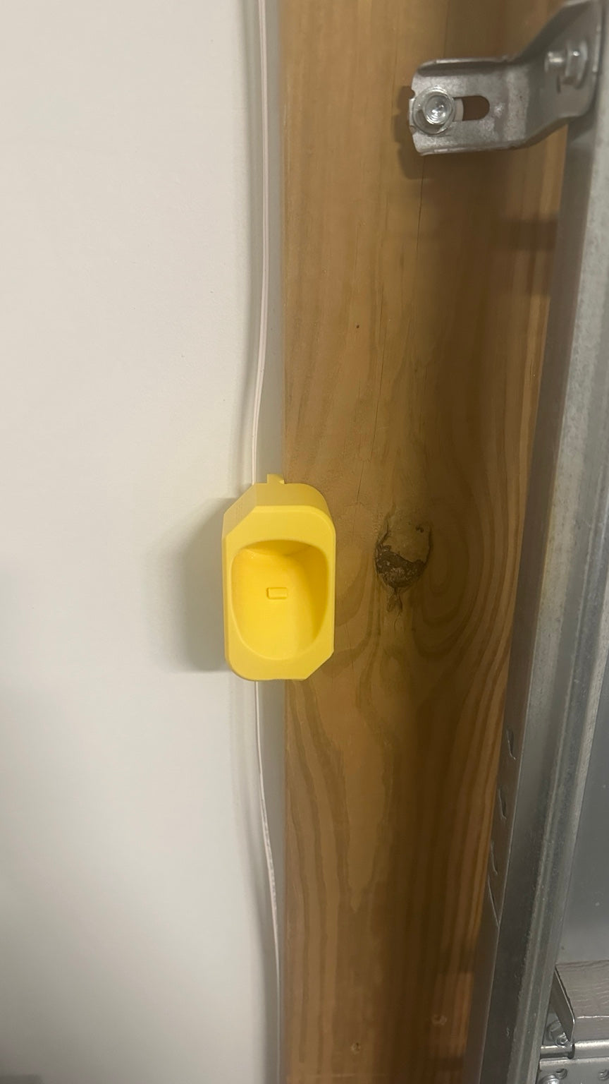 Yellow prototype corner mounted NACS charging dock without connector, showing position on garage wooden post