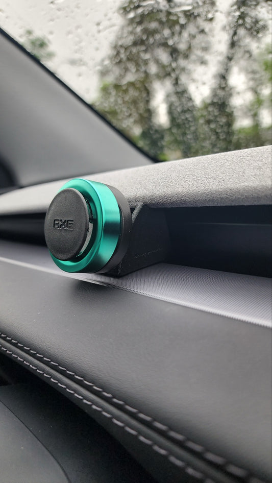 Tesla Model Y Juniper Highland front vent air freshener clip adapter installed on dashboard holding a sample circular freshener