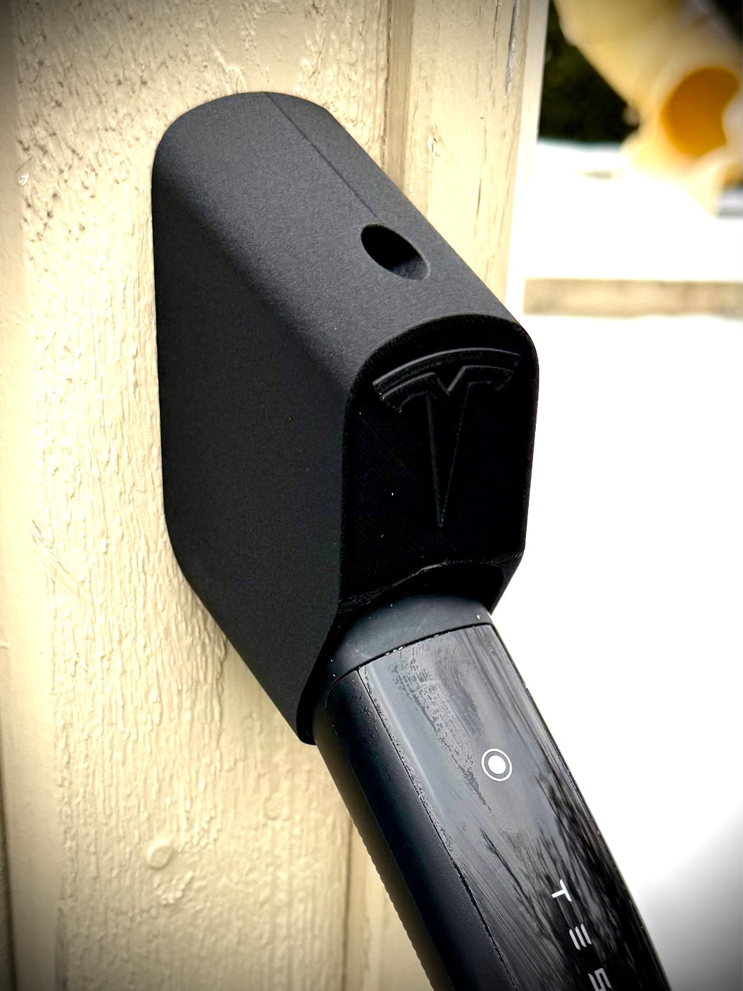 Close up of black 3D printed NACS charging connector holder with Tesla charging handle inserted