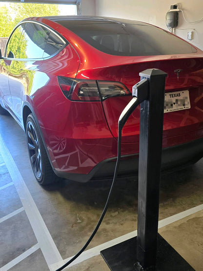 Tesla NACS wall dock mounted on garage post near red Tesla car