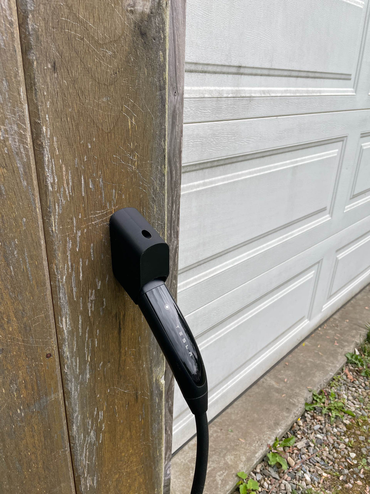 Secure-fit Tesla charging handle holder installed on a timber post alongside a garage door