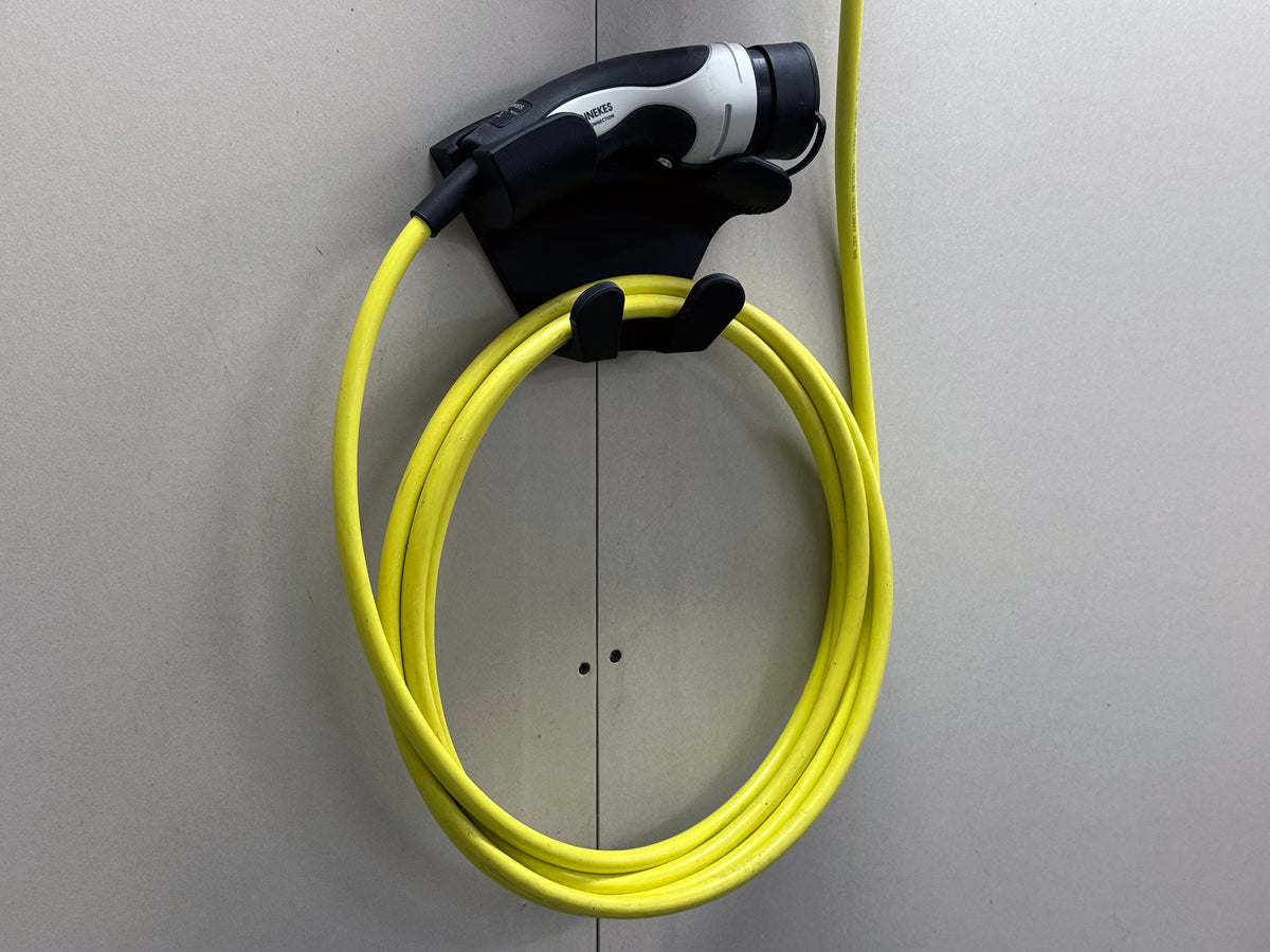 Universal EV charging handle and cable stored on black 3D printed wall mount with top cradle and lower hooks
