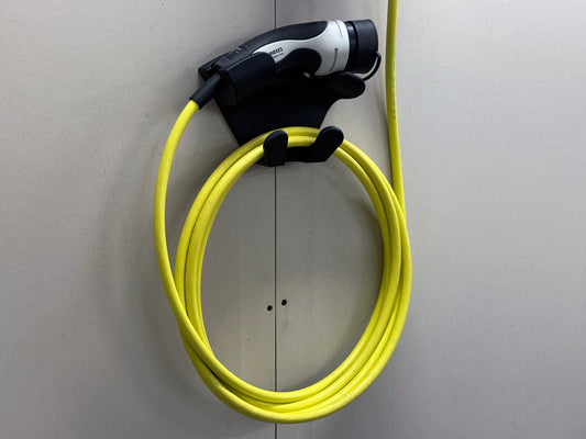 Universal EV charging handle and cable stored on black 3D printed wall mount with top cradle and lower hooks