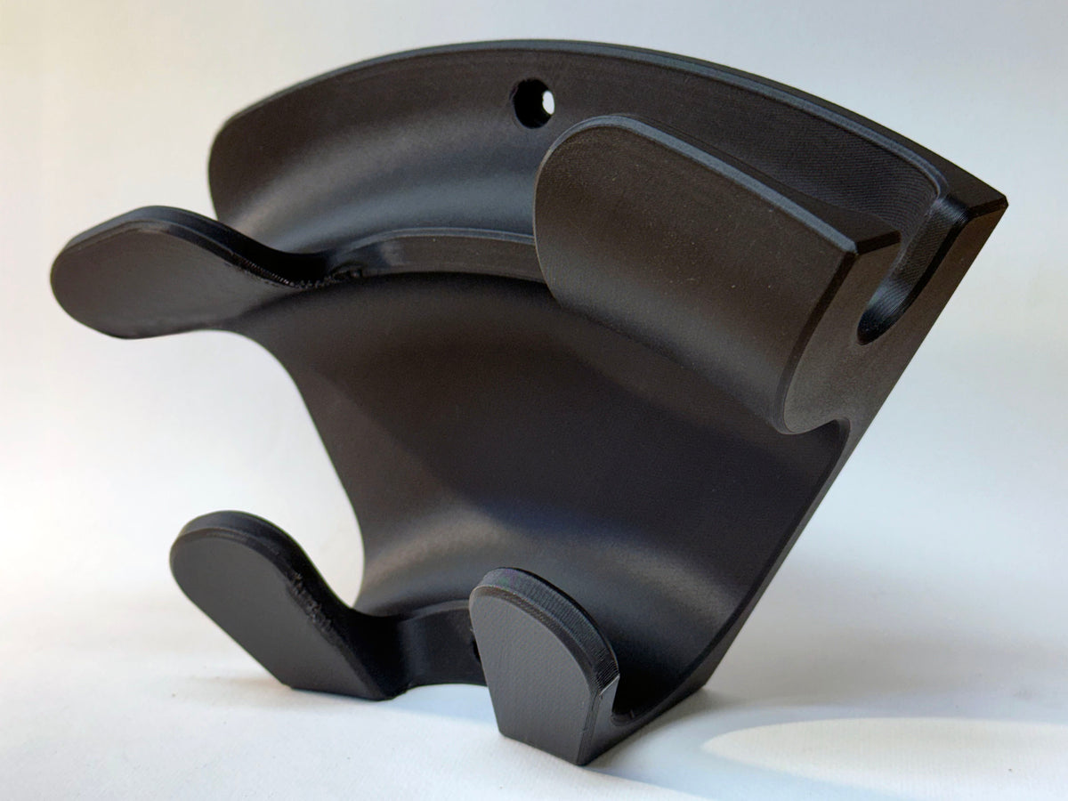 Detail of black wall organizer showing two mounting holes, upper plug cradle and lower cable hooks