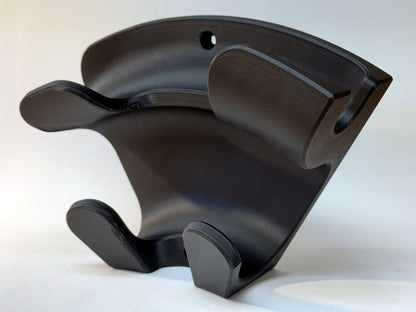 Detail of black wall organizer showing two mounting holes, upper plug cradle and lower cable hooks